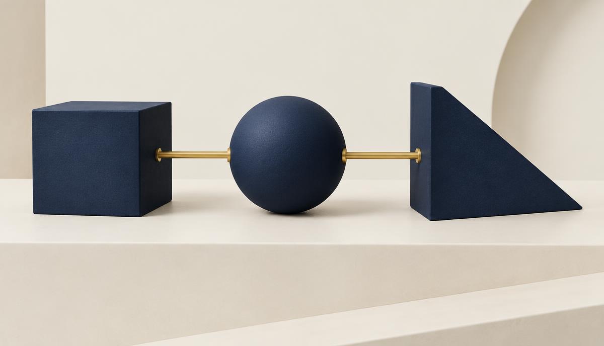 Três formas geométricas em azul-marinho conectadas por barras douradas sobre uma superfície creme